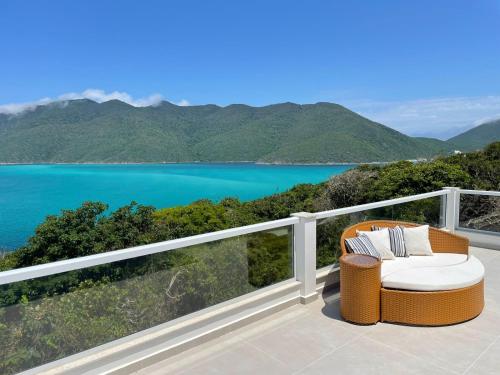 una silla en el balcón con vistas al lago en Casa aconchegante Pontal do Atalaia Vista Mar, en Arraial do Cabo