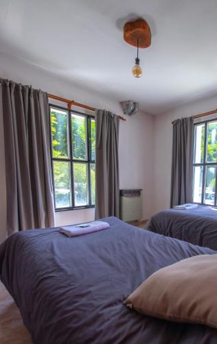 a bedroom with two beds and two windows at Hostería Punta Sur en Lago del Desierto no Chalten in Lago San Martin
