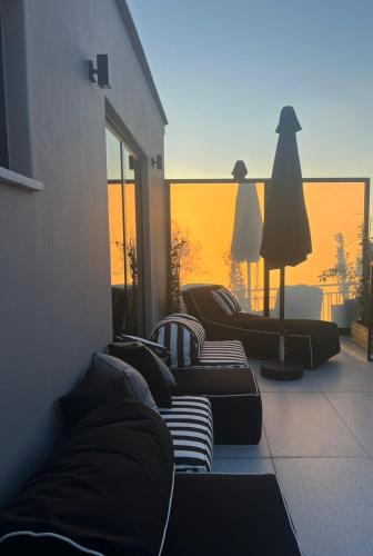 a group of couches sitting on a balcony with the sunset at Clyde Athens by Nin&Bau in Athens