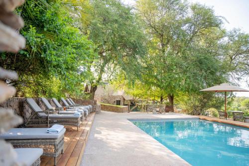 a swimming pool with lounge chairs and an umbrella at Thornybush Game Lodge in Thornybush Game Reserve