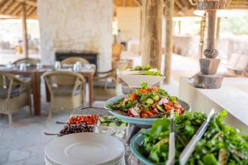 a table topped with bowls of salad and plates of food at Thornybush Game Lodge in Thornybush Game Reserve