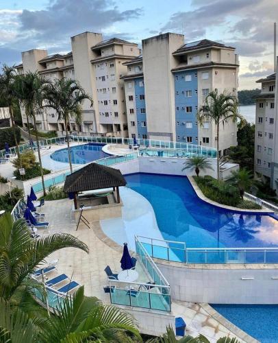 a large swimming pool with blue chairs and buildings at Cobertura Porto Real Suítes Mangaratiba - Vista Mar in Mangaratiba