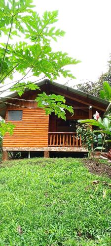 a wooden house with a green lawn in front of it at Arenal Rústic Lodge in Fortuna