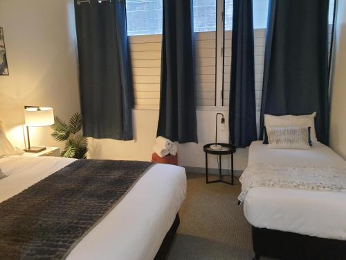 a bedroom with two beds and blue drapes at 1213/146 Sooning street, Nelly Bay, Magnetic Island. Qld 4819. One Bright Point. in Nelly Bay