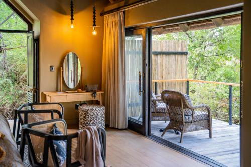 a room with a porch with chairs and a glass door at Thornybush Game Lodge in Thornybush Game Reserve