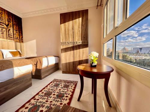 a room with two beds and a table and a window at New Museum Guest House, Pyramids View in Cairo