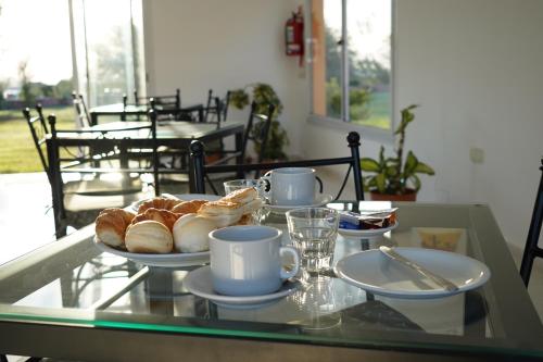 uma mesa de vidro com croissants e chávenas em La Posada de Salim em La Punta