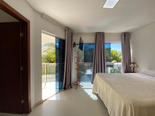 a bedroom with a bed and a large window at Village Rosa dos Ventos in Arraial d'Ajuda