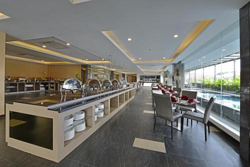 un restaurante con un bar con sillas y mesas en Serela Waringin by KAGUM Hotels, en Bandung