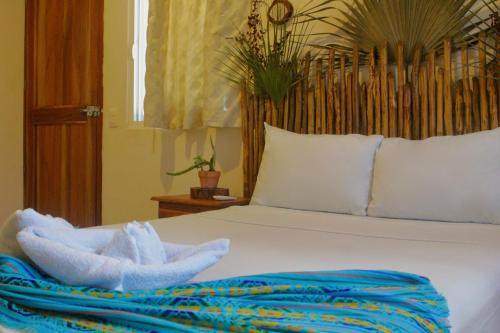 a bedroom with a white bed with a blue blanket at Hotel Jaiba Mahahual - Adults Only in Mahahual