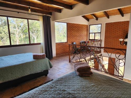 a bedroom with a bed and a balcony with windows at Villa Lakota By Natut Huasca in Huasca de Ocampo
