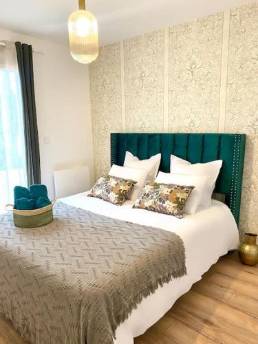a bedroom with a bed with a green headboard and pillows at Villa Contemporaine in Châtellerault