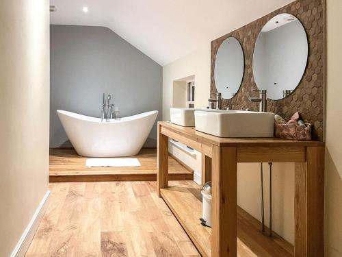 a bathroom with a tub and a sink and mirrors at Ivy Cottage in Grosmont