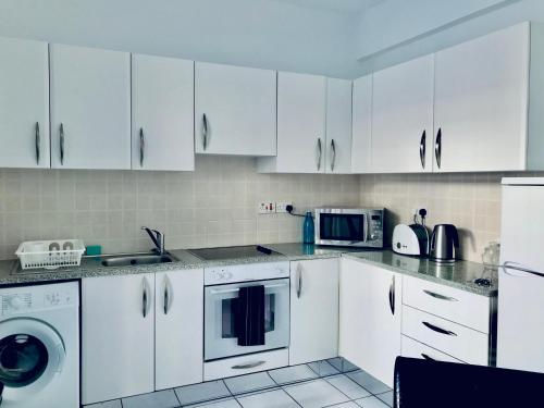 a white kitchen with white cabinets and a microwave at Diana Townhouse 5 in Paphos