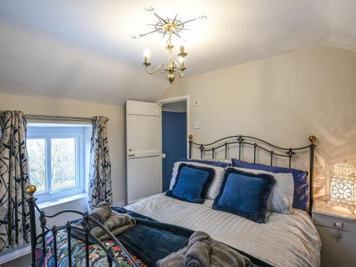 a bedroom with a bed with blue pillows and a chandelier at Bodeinion in Llanfair Caereinion