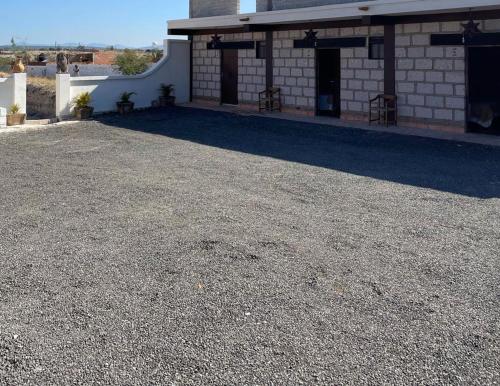 a building with a gravel parking lot in front of it at Rancho los olivos Habitaciones Campestres in San Miguel de Allende