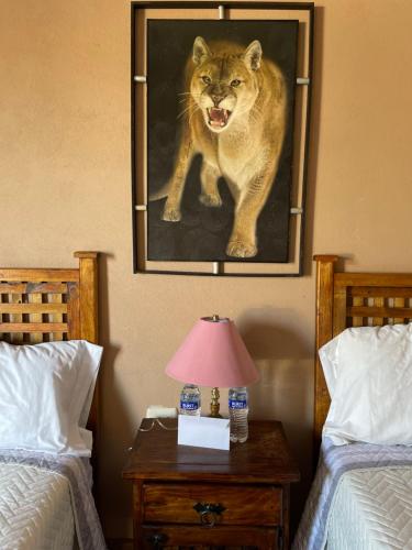 una pintura de un león en la pared junto a dos camas en Rancho los olivos Habitaciones Campestres en San Miguel de Allende