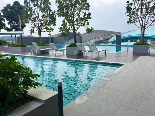 a swimming pool with chairs and a table and trees at Cozy Private Studio Apartment with View in Shah Alam