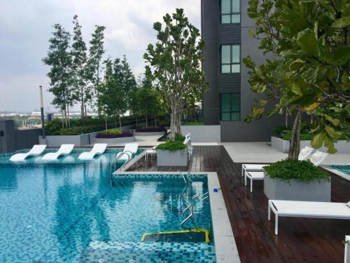 a swimming pool with white chairs and a building at Cozy Private Studio Apartment with View in Shah Alam