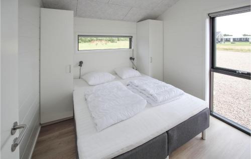 a bedroom with a large white bed with a window at Cozy Home In Samsø With Sauna in Nordby