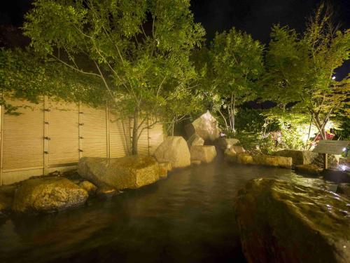 a stream of water with rocks and trees at night at Hotel Okura JR Huis Ten Bosch in Sasebo