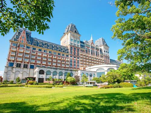a large building with a green park in front of it at Hotel Okura JR Huis Ten Bosch in Sasebo