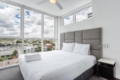a bedroom with a large white bed with large windows at Two bedroom apartment on Ann Street Fortitude Valley By Serain Residences in Brisbane