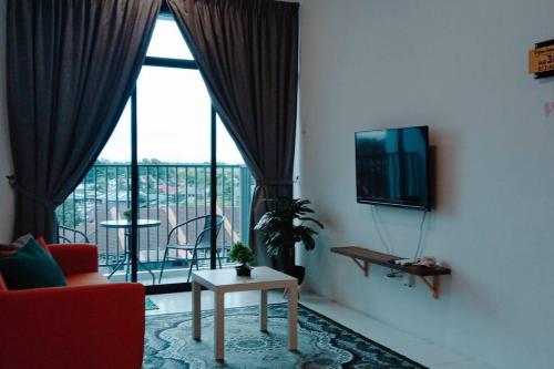 uma sala de estar com um sofá, uma televisão e uma varanda em D'yana Imperio Homestay em Alor Setar