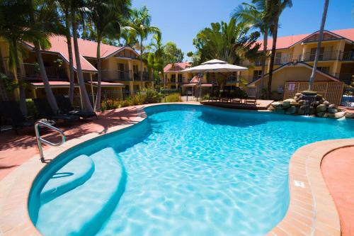 a large swimming pool in a resort with palm trees at Beach Court Holiday Villas 4n each guest get free Day trip Kens Klassic Kombi in Airlie Beach