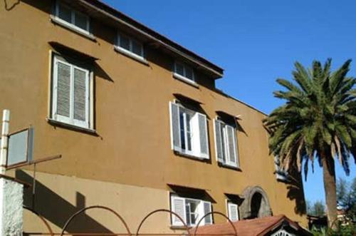 un bâtiment avec des fenêtres et des palmiers en face de celui-ci dans l'établissement Villa Orchidea, à Sorrente