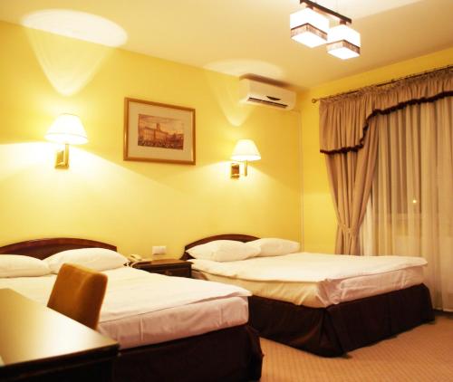 a hotel room with two beds and a table at Hotel Wilga by Katowice Airport in Pyrzowice