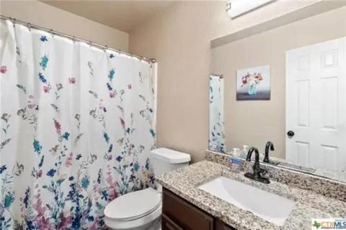 a bathroom with a shower curtain with a toilet and a sink at Cozy 3bd/2bath staycation near fort hood in Killeen