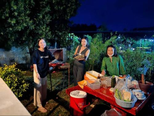 un grupo de mujeres de pie alrededor de una mesa con comida en บ้านสไตล์คาเฟ่วังน้ำเขียว en Ban Kom