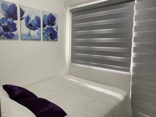 Katei elegantly designed 1-bedroom facing amenity في مانيلا: غرفة نوم مع نافذة بها لوحتين على الحائط
