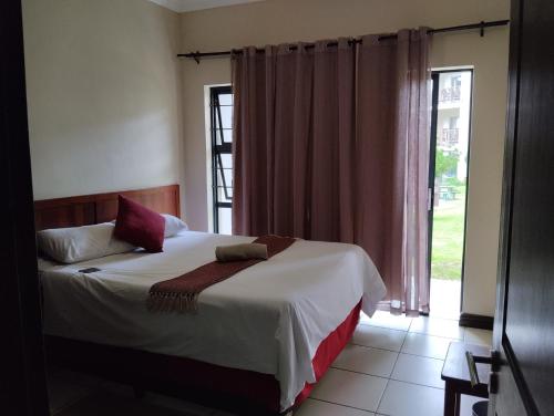 ein Schlafzimmer mit einem Bett und einem großen Fenster in der Unterkunft Topanga Holiday Apartment in Uvongo Beach
