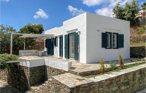 a white house with green shutters and a stone wall at Lovely Home In Sifnos With Wifi in Sifnos