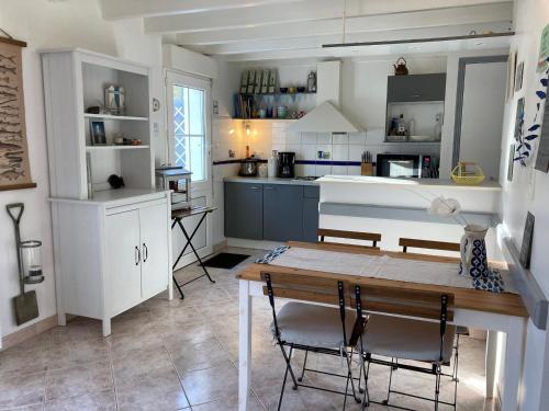 une cuisine avec une table et des chaises dans une pièce dans l'établissement Charmante Maison avec Jardin, Terrasse et Parking - Animaux Acceptés - FR-1-418-196, au Palais