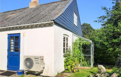 a white house with a blue door and a greenhouse at Awesome Home In Samsø With Wifi in Ballen