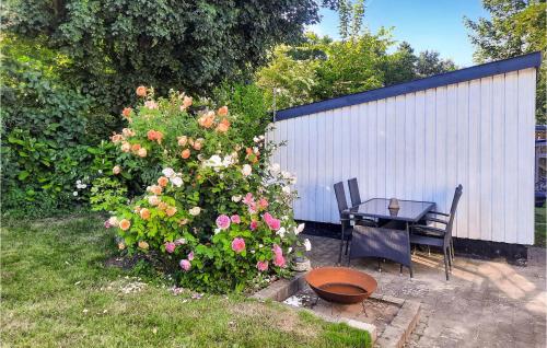 a garden with a table and a bush with flowers at Awesome Home In Samsø With Wifi in Ballen
