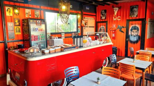 Hotel Bonito Motobox - HOTEL CONTAINER في بونيتو: مطعم بجدران حمراء وطاولات وكراسي