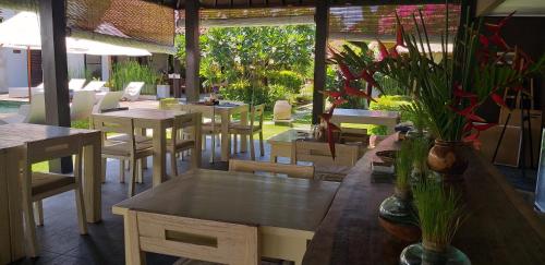 un restaurante con mesas, sillas y plantas en Katala Suites and Villas en Sanur