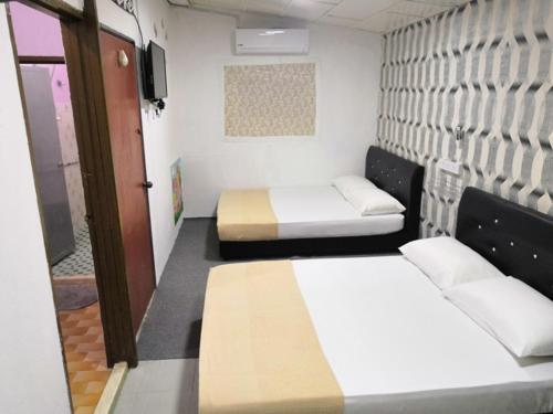 a small room with two beds and a tv at JSW Inn in Gelugor