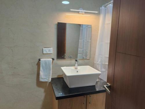uma casa de banho com um lavatório branco e um espelho. em Tara Suites Premium rooms in Central Indiranagar em Bangalore