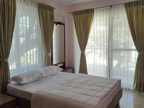 um quarto com uma cama grande com cortinas e janelas em Tara Suites Premium rooms in Central Indiranagar em Bangalore