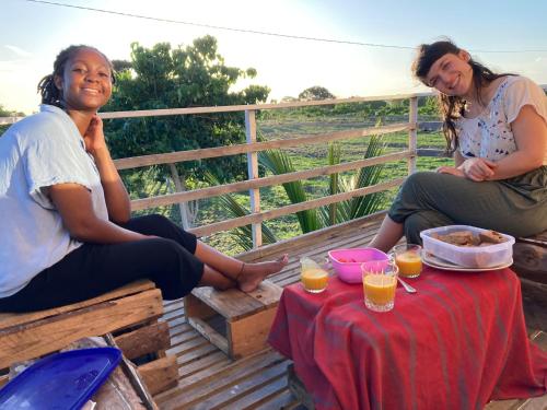 due donne sedute su un ponte con un tavolo con bevande di Bagamoyo Home Stay a Bagamoyo
