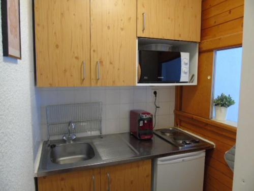 une petite cuisine avec un évier et un micro-ondes dans l'établissement Charmant studio rénové, proche télécabine, balcon sud, animaux acceptés, draps inclus, casier à ski - FR-1-561-52, à Valfréjus