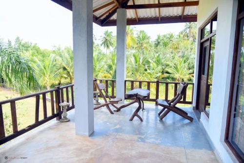 eine Veranda mit zwei Stühlen und einem Tisch darauf in der Unterkunft ohm lagoon home in Tangalle