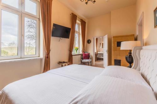 a bedroom with a white bed and a window at Schlosshotel Gross Koethel in Hohen Demzin