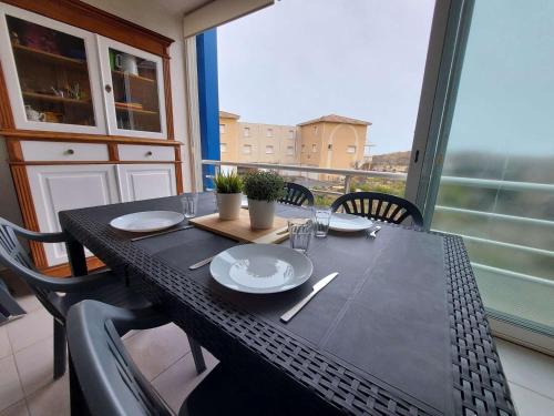 une table noire avec des plaques sur le balcon dans l'établissement Appartement climatisé 2P cabine, 50m de la plage, parking, loggia, équipements modernes - FR-1-326-747, à Marseillan