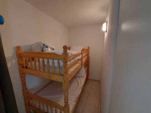 un lit superposé en bois dans une petite pièce dans l'établissement Appartement climatisé 2P cabine, 50m de la plage, parking, loggia, équipements modernes - FR-1-326-747, à Marseillan